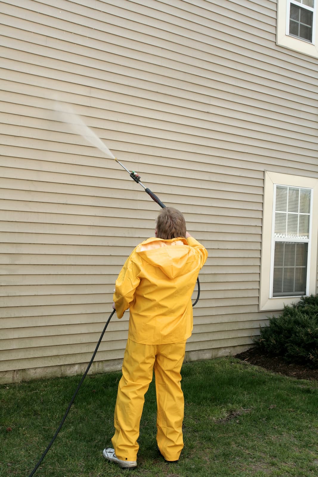Technician soft washing a home's exterior siding